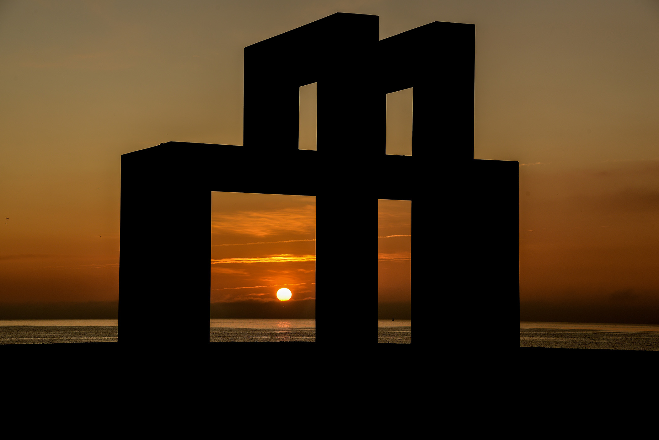 Catène de containers sur la plage du Havre, arches monumentales au coucher du soleil