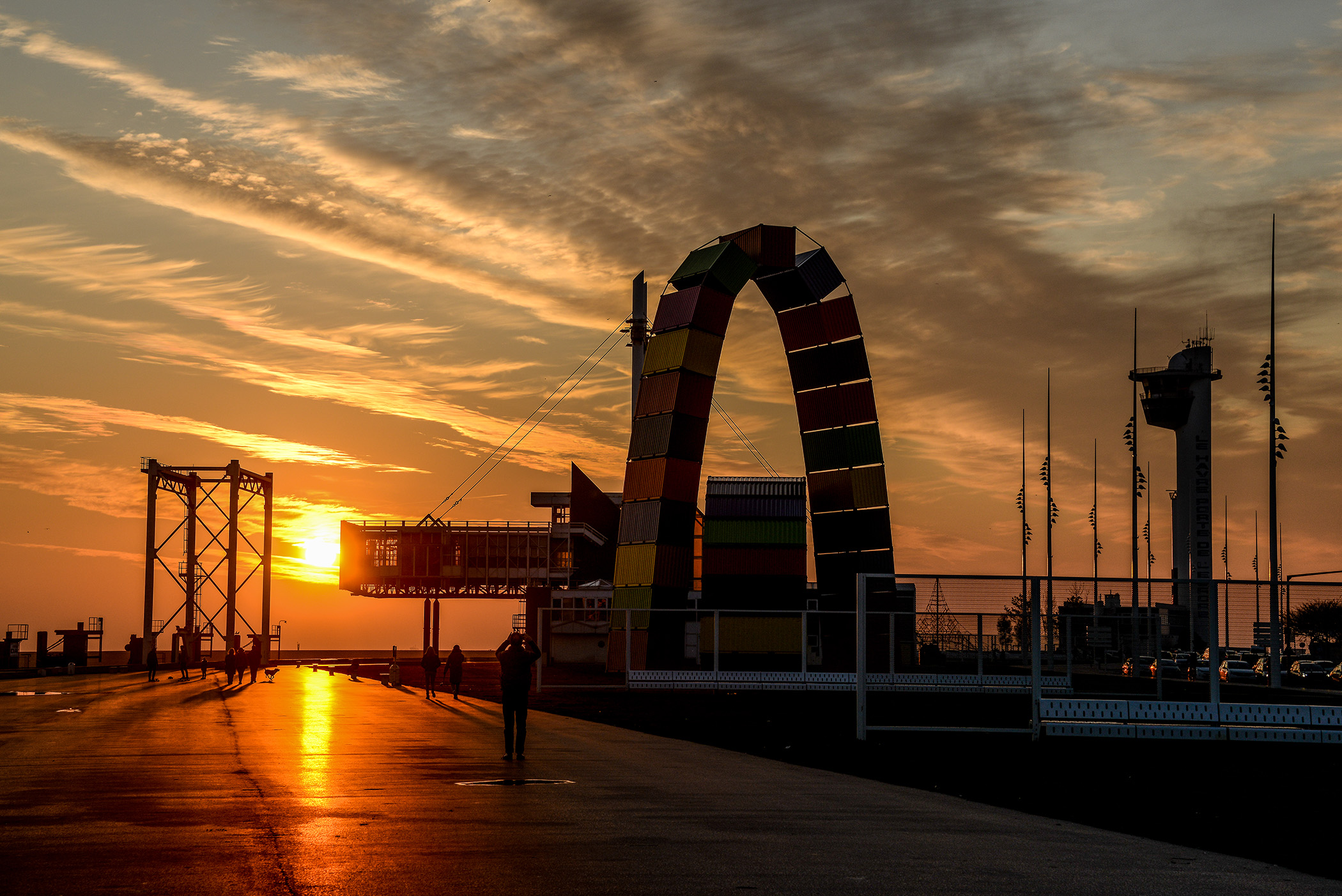 Catène de containers sur la plage du Havre, arche colorée cadrant le soleil du matin