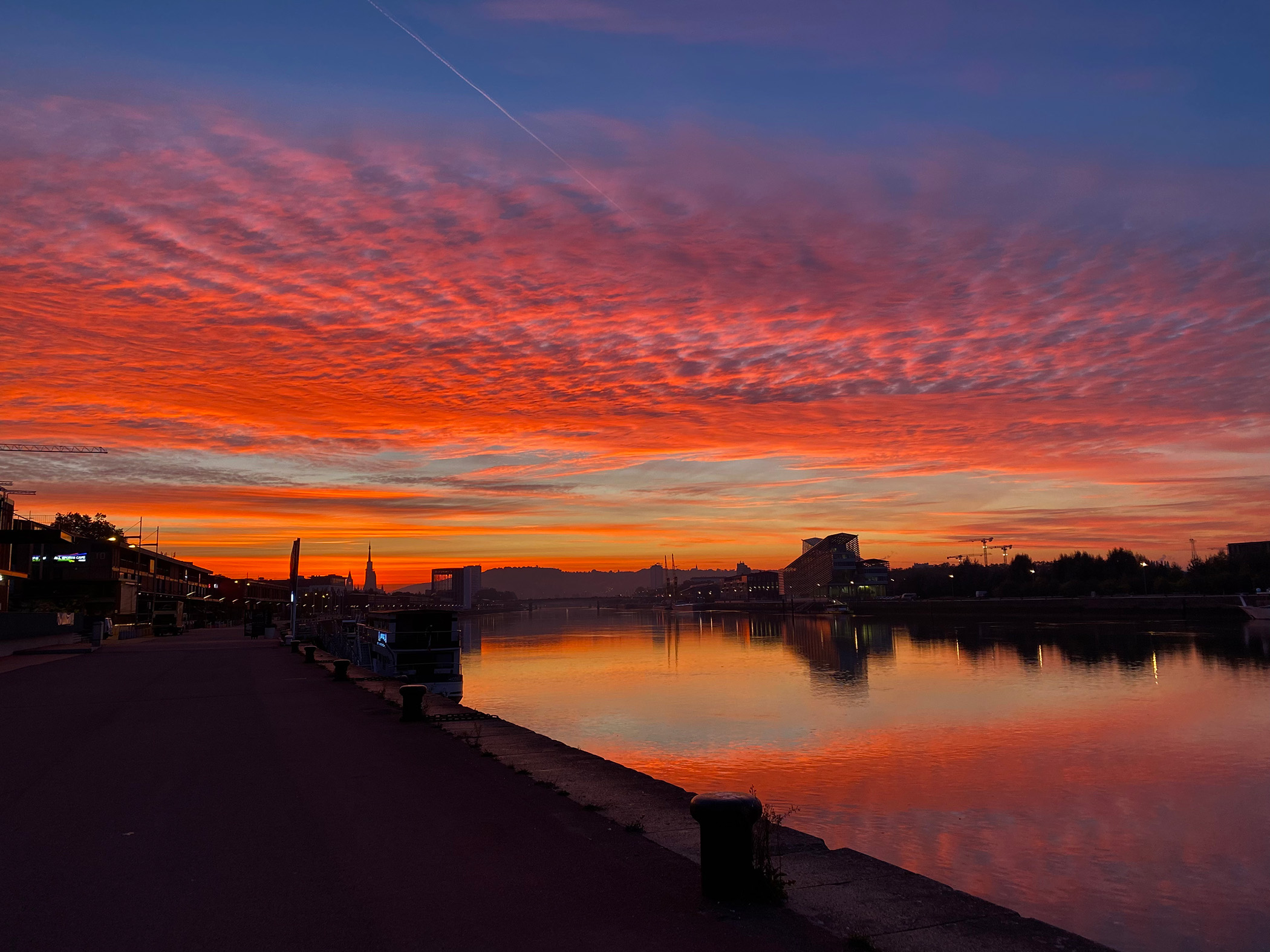 Coucher de soleil flamboyant sur la Seine à Rouen, nuages ondulés rouges et reflets sur l’eau calme