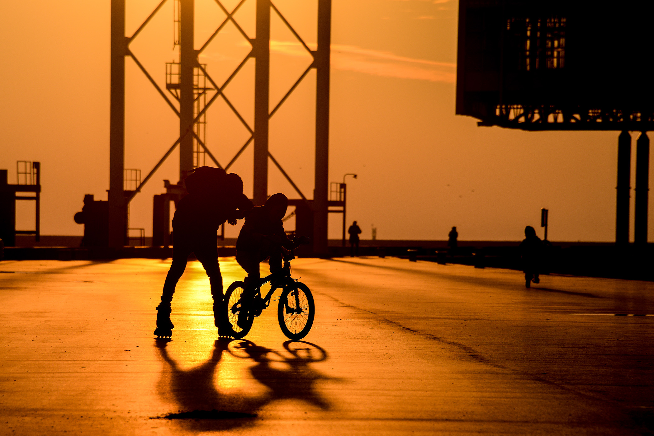 Front de mer du Havre au coucher du soleil, silhouettes en mouvement entre roller, vélo et jogging